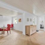 Esszimmer mit roten Stühlen und Holzboden. Flur mit Sideboard und Bildern an der Wand.