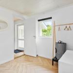 Zimmer mit Holzboden, Kleiderständer und Fenster mit Blick auf Grün.