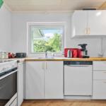 Küche mit weißen Schränken, Holzoberfläche und Fenster zum Garten.