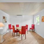 Esszimmer mit runden Tisch, roten Stühlen und Holzboden