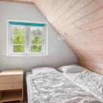 Schlafzimmer mit Dachschrägen, Fenster und Bett.