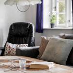 Ein Wohnzimmer mit Sofa, Sessel, Tisch und Fenster.