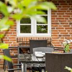 Terrasse mit Tisch und Stühlen vor Backsteinhaus mit Fenster