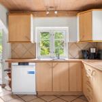 Küche mit Holzschränken, Spüle und Blick auf Garten