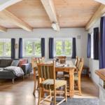 Ein Raum mit Essbereich, Sofa und Holzboden. Holzdecke mit Balken.