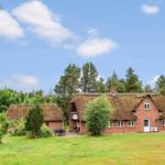 Rotes Backsteingebäude mit Strohdach und Garten unter blauem Himmel.
