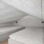 Zwei Betten unter Dachschrägen mit weißen Matratzen und Holzboden.
