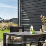 Terrasse mit Tisch, Stühlen und Blick auf Grasland und Häuser.