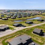Aerial view of holiday homes with green fields and a small pond.
