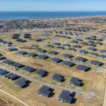 Aerial view of holiday homes near the sea with roads and small ponds.