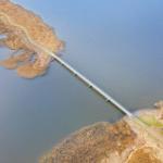 Eine Brücke überspannt einen See und verbindet zwei Ufer mit Grasland.