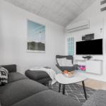 Wohnzimmer mit Sofa, Sessel und Fernseher. Blick in Schlafzimmer.