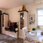 Essbereich mit runden Tisch und weißen Stühlen, daneben Wohnbereich mit TV und Schränken.