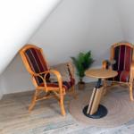 Zwei Rattan-Stühle mit Streifenbezug und runder Tisch auf Teppich.