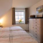 Schlafzimmer mit Doppelbett, Fenster und Kleiderschrank.