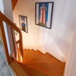 Holzgetreppe mit Geländer und Wandbildern an der Wand.