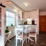 Küche mit Essbereich, Holztreppe und Glasvitrine mit Geschirr.