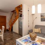 Wohn- und Essbereich mit Holztreppe, Sofa und Küchenzeile.