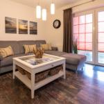 Wohnzimmer mit grauem Sofa, weißem Tisch und Holzboden.