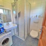 Badezimmer mit Dusche, Waschbecken und Waschmaschine.