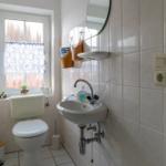 Badezimmer mit Toilette, Waschbecken und Spiegel an der Wand.