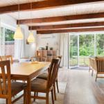 Essbereich mit Holztisch und Stühlen, Sitzgelegenheiten und Blick auf Garten.