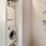 Waschmaschine und Trockner in einem Raum mit Dusche.