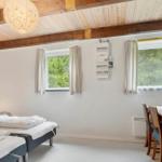 Zimmer mit Bett, Tisch, Fenstern und Holzdecke mit Balken.