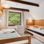 Zimmer mit zwei Betten, Holzwand und Fenster mit Blick auf Bäume.