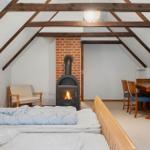 Schlafzimmer mit Kamin, Tisch und Stühlen unter Holzbalkendecke