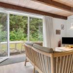 Wohnbereich mit Holzdecke, Glasfront und Gartenansicht.