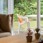 Durch das Fenster ist eine Terrasse mit Stuhl und Tisch zu sehen.