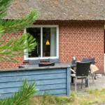 Rotes Backsteinhaus mit Strohdach und Außenbereich mit Tisch und Stühlen.