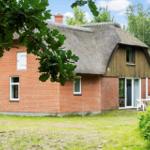 Haus mit strohgedecktem Dach und rotem Backstein. Gartenbereich mit Tisch und Stühlen.