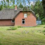 Rotes Backsteingebäude mit Strohdach und Fenstern im Grünen.