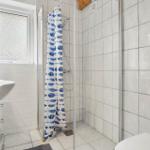 Badezimmer mit Dusche, Waschbecken und Toilette. Duschvorhang mit Fischmuster.