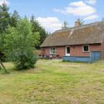 Rotes Backsteingebäude mit Strohdach, Garten und Grillplatz.
