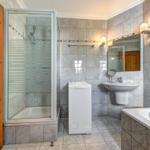 Badezimmer mit Dusche, Waschmaschine, Waschbecken und Badewanne.