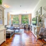 Wohn- und Essbereich mit Holzboden, Sofa, Tisch und Fenstern.