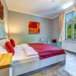 Schlafzimmer mit Bett, Fenster und Kunstwerken an den Wänden.