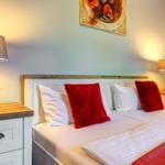 Schlafzimmer mit Bett, zwei Nachttischen und Lampen. Wandbild über dem Bett.