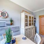 Esszimmer mit Tisch, Stühlen, weißen Schränken und Holztür.