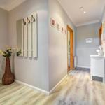 Flur mit Holzboden, Spiegelschrank und Vase mit Blumen.