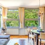 Esszimmer mit Tisch, Stühlen und Blick auf grüne Bäume.