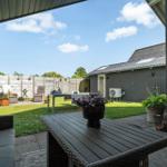 Terrasse mit Tisch, Sitzgelegenheiten und Garten. Hinterhof mit Grill und Pflanzen.