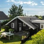Schwarze Ferienhaus mit Garten und Außentisch unter blauem Himmel.