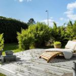 Holzterrasse mit Liegestuhl, Pflanzen und Gartenmöbeln.