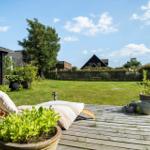 Hinterhof mit Holzterrasse, Liegestuhl und Grünflächen. Im Hintergrund sind Häuser und Bäume sichtbar.