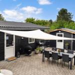 Terrasse mit Tisch, Stühlen und Sonnensegel. Grill und Liegestühle sind vorhanden.