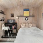 Schlafzimmer mit Holzwand, Bett, Schreibtisch und Fenster.